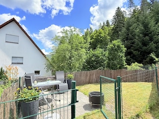 eingezäunte Esstischgruppe mit Grill und Sonnenschirm