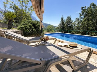 Der Pool mit Sonnenliegen und Sonnenschutz