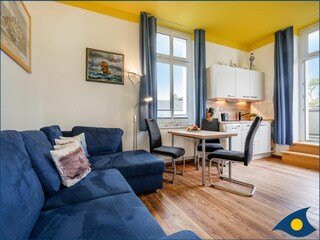 Wohnzimmer mit offener Küche und Zugang zum Balkon