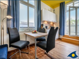 Wohnzimmer mit offener Küche und Zugang zum Balkon