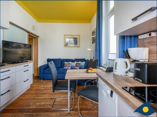Wohnzimmer mit offener Küche und Zugang zum Balkon
