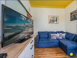 Wohnzimmer mit offener Küche und Zugang zum Balkon