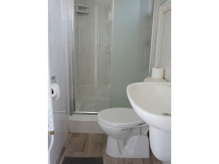 Badezimmer mit Düsche , Waschbecken und Toilette.