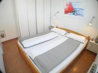 Schlafzimmer mit Doppelbett und großem Kleiderschrank.