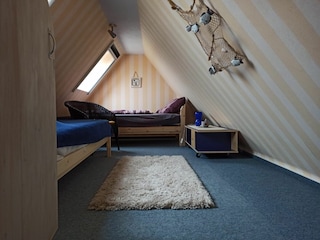 Dachzimmer mit zwei Betten von Treppe aus