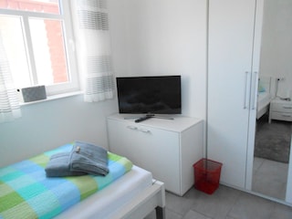 Schlafzimmer mit Fernseher und Kleiderschrank