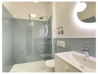 Das moderne Bad mit bodengleicher Dusche und WC.