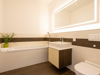 1. Badezimmer mit Badewanne und großem Wandspiegel