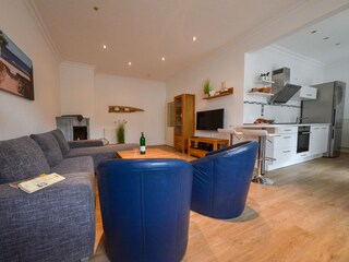 Wohnzimmer mit TV, Kamin und Zugang zur Küche