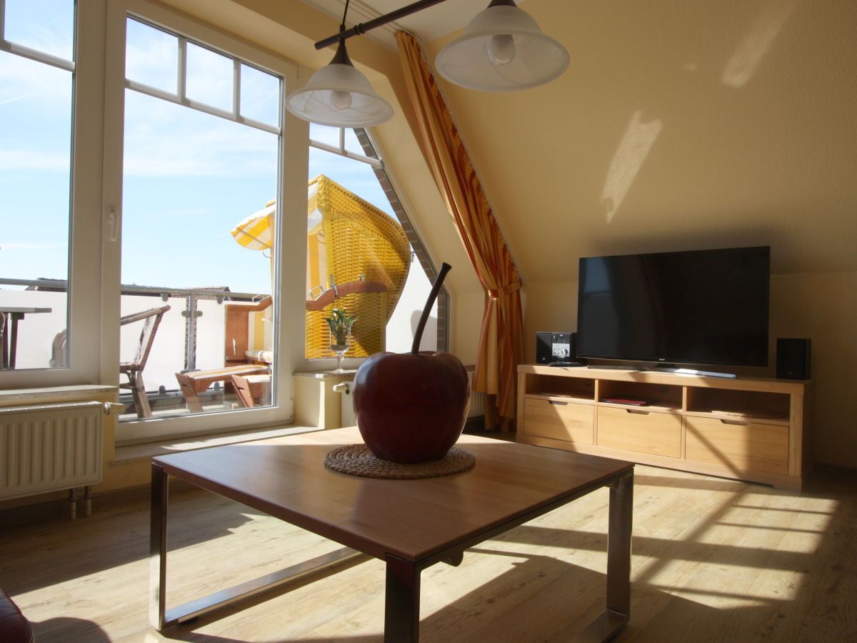 Sonniger Wohnraum mit Blick auf Balkon mit Strandkorb.