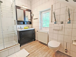 Badezimmer mit Dusche, Doppelwaschtisch, Fön und WC.
