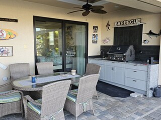 Covered outdoor kitchen with grill and dining area