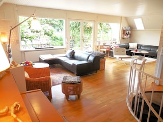 helles Wohnzimmer mit zwei Sitzgruppen und Klavier