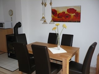 Esstisch mit 6 bequemen Stühlen; daneben der Kamin