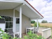 Überdachte Terrasse mit Esstisch, Stühlen und Deckchair