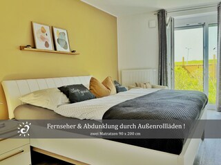 Schlafzimmer mit Fernseher und  Außenrollläden