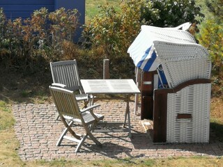 Terrasse mit Gartenstühlen und Strandkorb