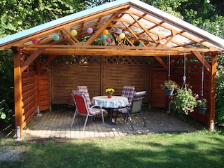 überdachter Grillplatz mit Gartenmöbeln