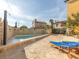 Außendusche und Sonnenliegen am Swimmingpool
