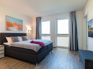 erstes Schlafzimmer mit bequemen Boxspringbett und Bad