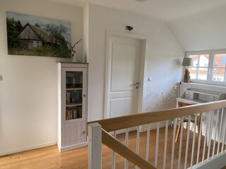 Leseschrank und Schreibsekretär unter der Reetdachgaupe