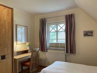 Schlafzimmer mit Doppelbett und Schreibtischecke