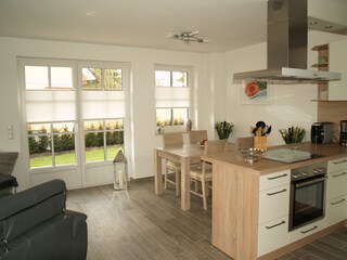 Kochinsel mit Esstisch und Blick in den Garten