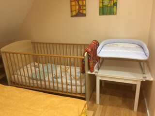 Gitterbett und Wickelplatz im Schlafzimmer