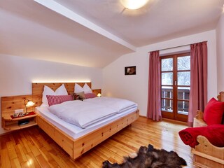 Zirbenschlafzimmer mit Zugang zum Balkon.