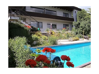 Blick auf Fewo mit Terrasse und Pool.