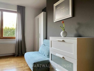 Schlafzimmer mit Sofa & moderner Kommode