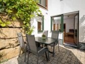 Terrasse im Süden mit Natursteinmauer u. Sonnenschirm.