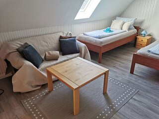 Großes Schlafzimmer mit Sofa, Tisch, Laminatboden