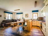 Living room with corner bench group and kitchen.