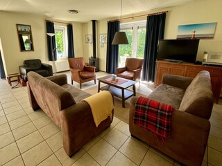Wohnbereich mit Sofas Sesseln, Fernseher und Kaminofen