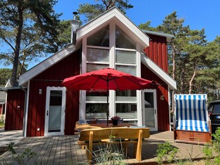 sonnige Terrasse mit Strandkorb, Holzsitzgarnitur und Sonnenschirm