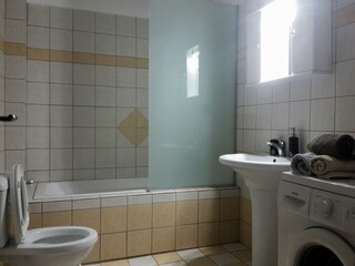 Badezimmer mit Badewanne und Waschmaschine