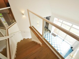 Über die offene Holztreppe gelangen zu den Schlafräumen im Obergeschoss.