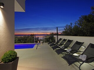 Der Pool mit Sonnenliegen und Meerblick