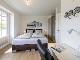 Schlafzimmer mit Boxspringbett und Zugang zum Balkon