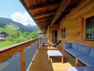 Großzügiger Balkon mit Couch und Deckchairs