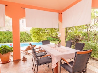 überdachte Sitzgruppe mit Blick auf den Swimmingpool