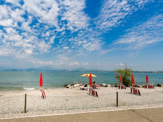 Strand mit Liegestuhlverleih neben dem Seezugang