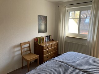 Schlafzimmer 1 mit Kommode und kleiner Bibliothek