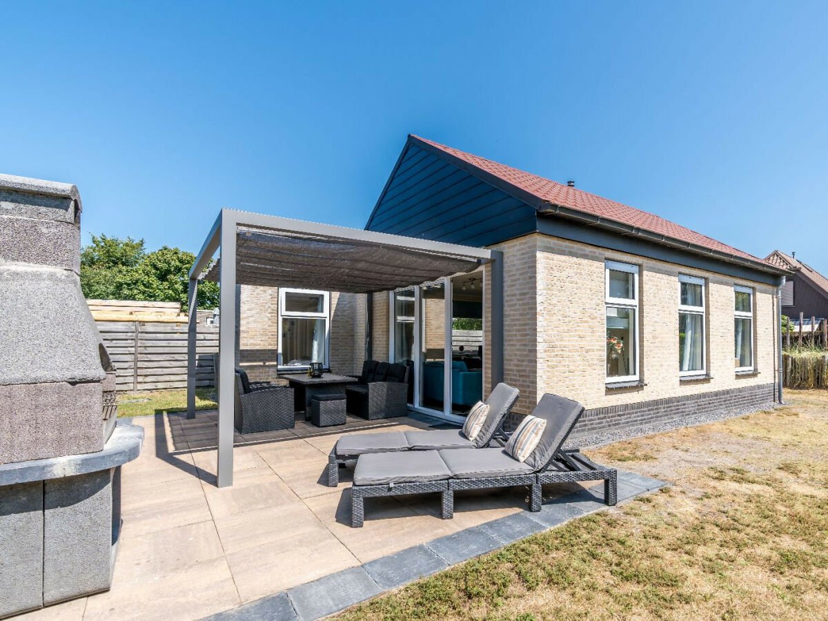 Ferienhaus mit sonnigem Garten, Lounge-Ecke und Grill.