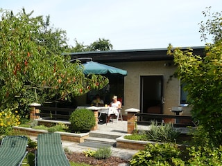 Terrasse mit Sonnenschirm, Stühlen und Liegen