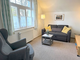 Wohnzimmer mit Couch, Sessel und Flachbild-TV