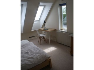 Schlafzimmer mit Schreibtisch und Morgensonne