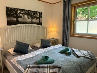 großes Doppelbett mit BlickschuFliegengitter am Fenster