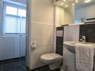 Auch das Badezimmer mit bodengleicher Dusche ist in freundlichen Farben gehalten.